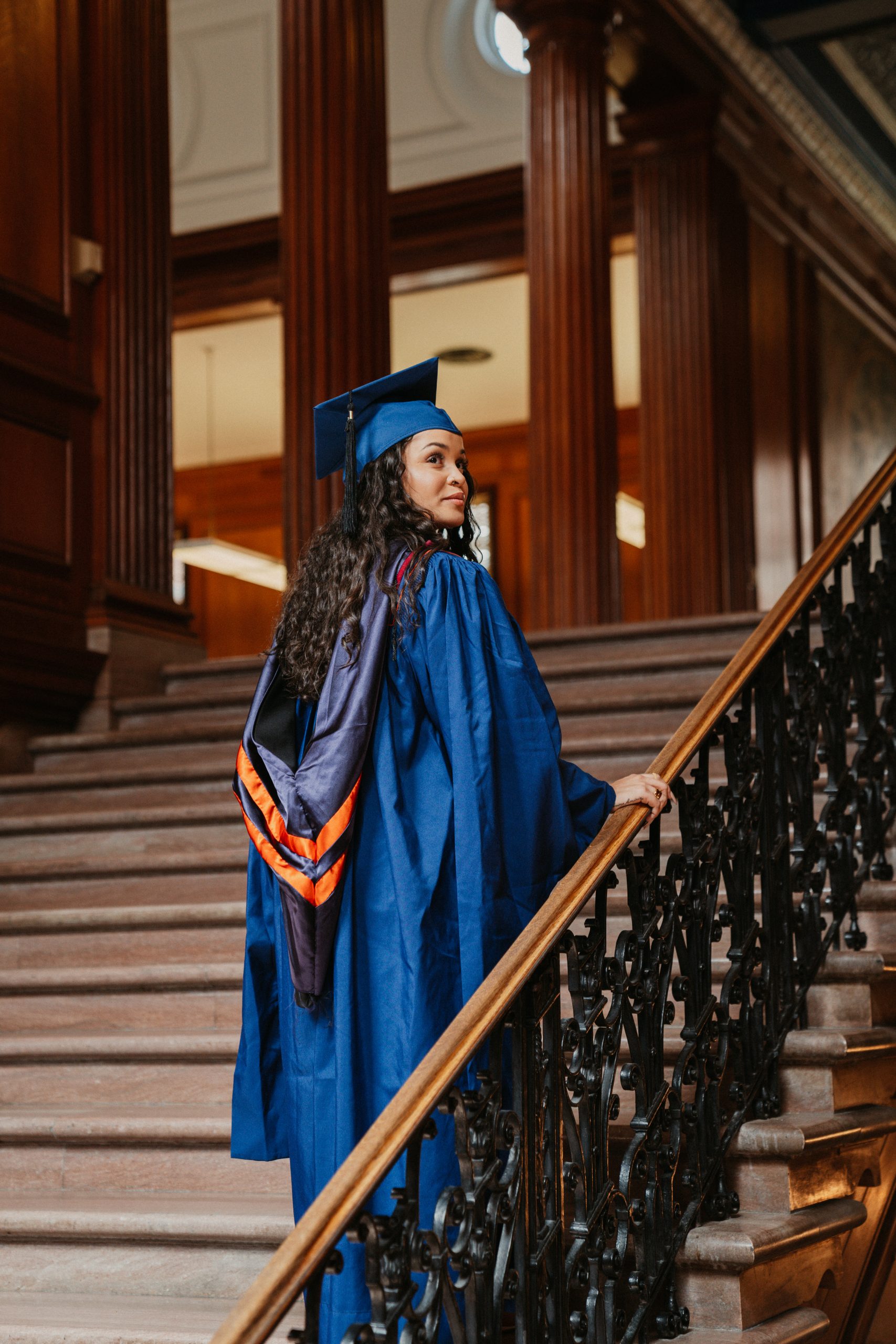 Paris in a long blue graduation gown in front of a fountain of the University of Illinois campus